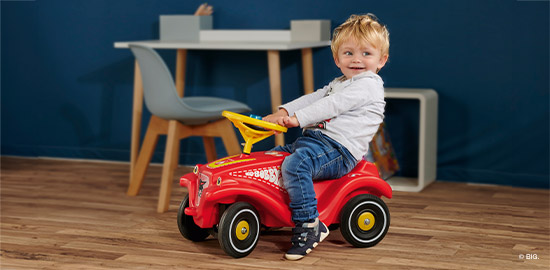 Kleinkind mit rotem Feuerwehr Bobby Car